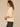 Macadamia Below Elbow Blouson Sleeve Round Neck Half Button Placket Embroidered Front Pleated Back Shirttail Hem Woven Top